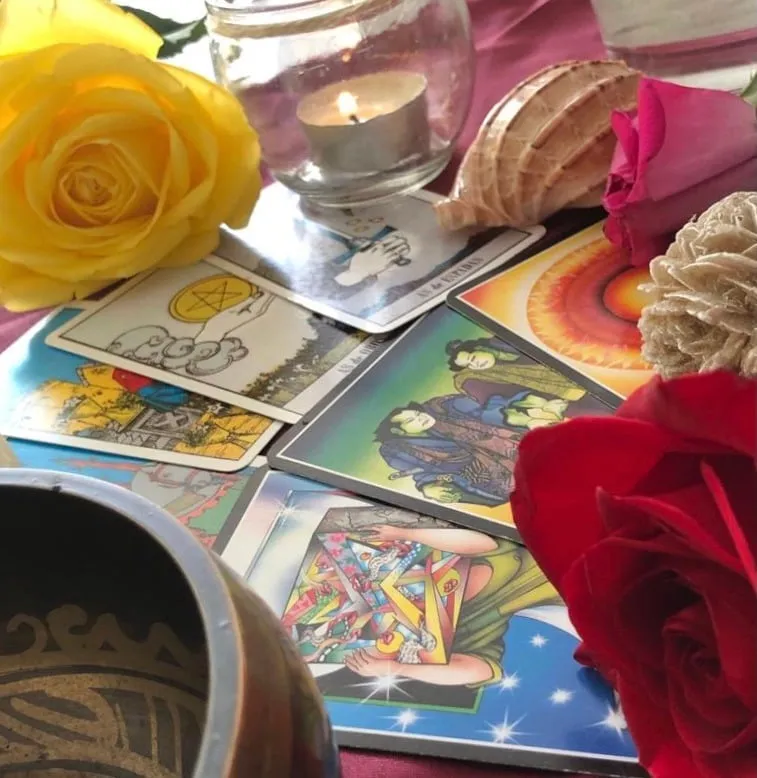 Cartas de tarot, una vela y rosas sobre la mesa