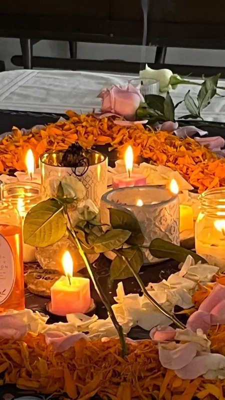 Lit candles among marigolds and roses on an altar
