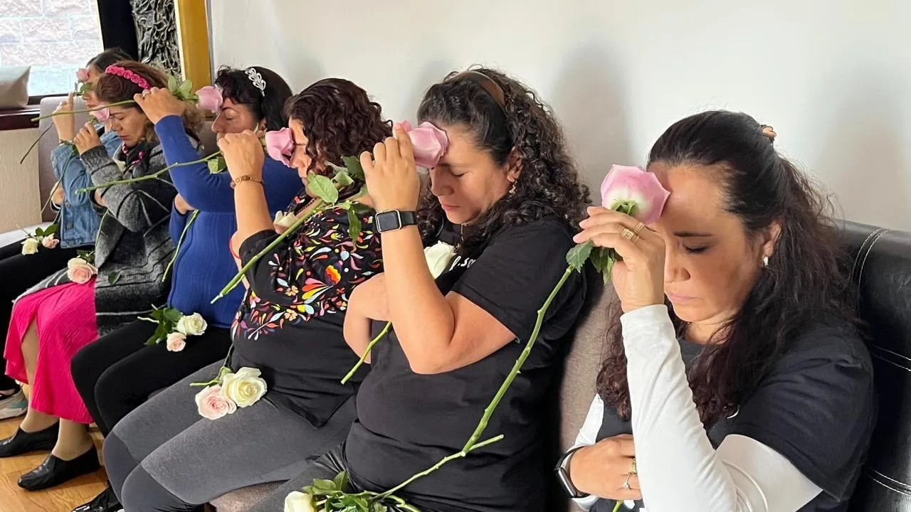Women meditating with pink roses held to their foreheads