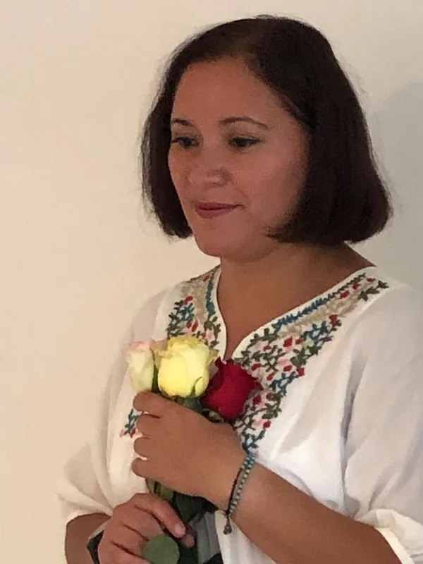 Zinnia E. Pavón holding yellow, pink and red roses